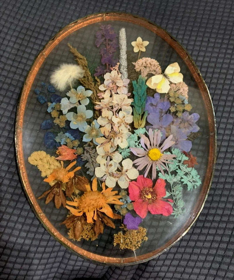 Oval glass frame with copper edge and colorful dried flowers arrangement