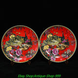 Pair of round red enamel porcelain plates with peacock, peony-style flowers, and gilt rim