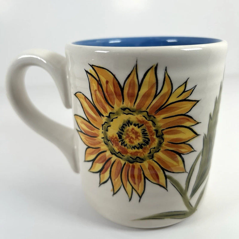 White earthenware coffee mug with blue rim and painted sunflower