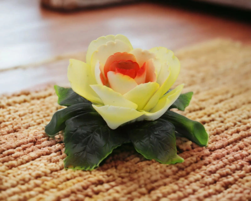 Ceramic peony flower figurine with pale yellow petals, red center, and green leaves