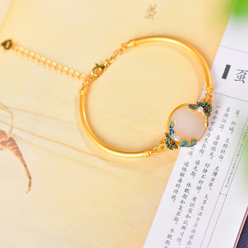Gold-tone hand chain with circular link and blue-and-gold peony flower charm