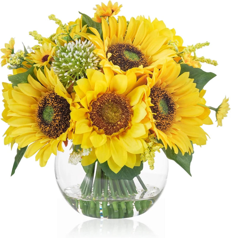 Artificial sunflower centerpiece arrangement in clear glass vase with green leaves