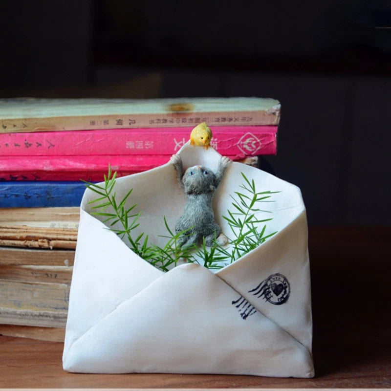 White resin wall planter in envelope shape with small animal figurine and green plants