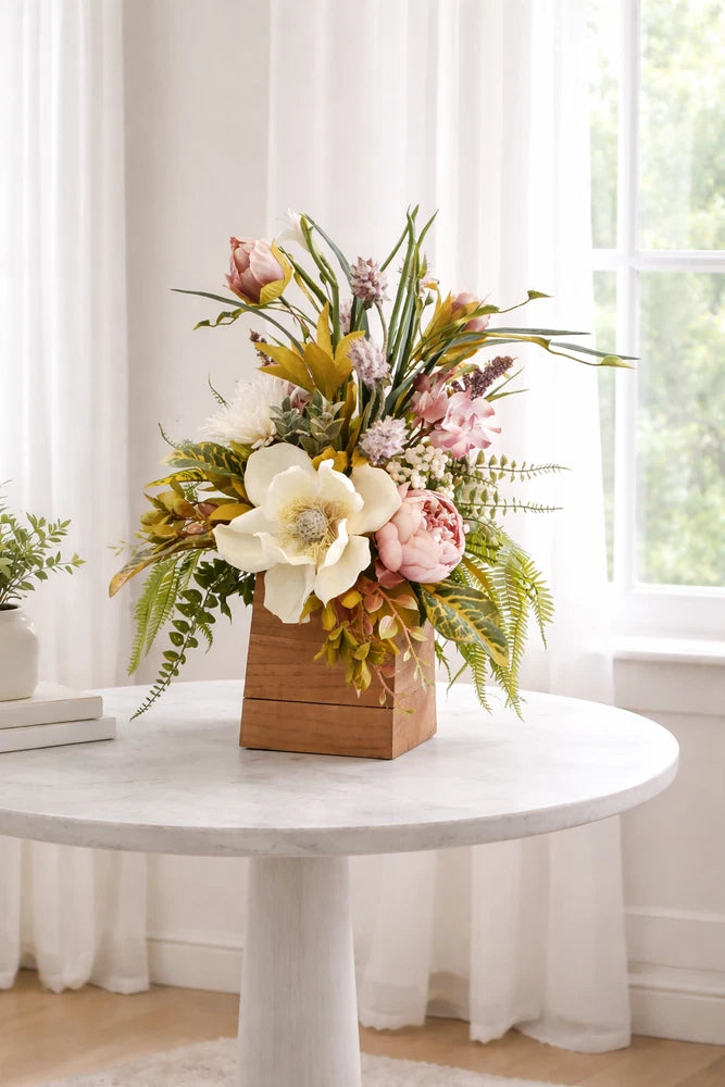 Spring floral centerpiece in wooden box with cream, pink, and yellow blooms
