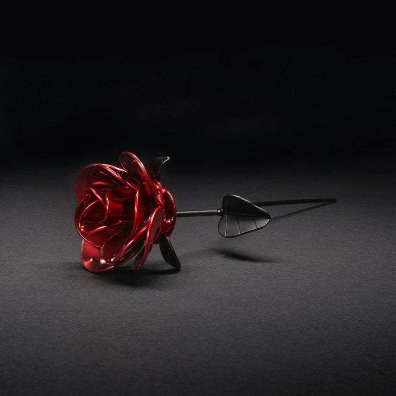 Welded metal steampunk rose with red petals and black accents on a spike stem