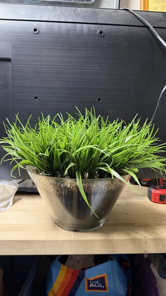 Artificial grass plant in silver glass pot with dense green blades