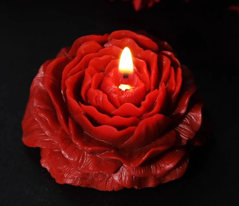 Red peony-shaped candle with carved petals and three small flames