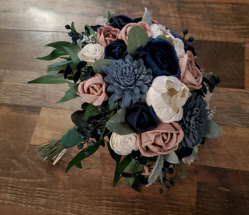 Artificial bridal bouquet with mauve, dusty blue, and navy flowers and green leaves