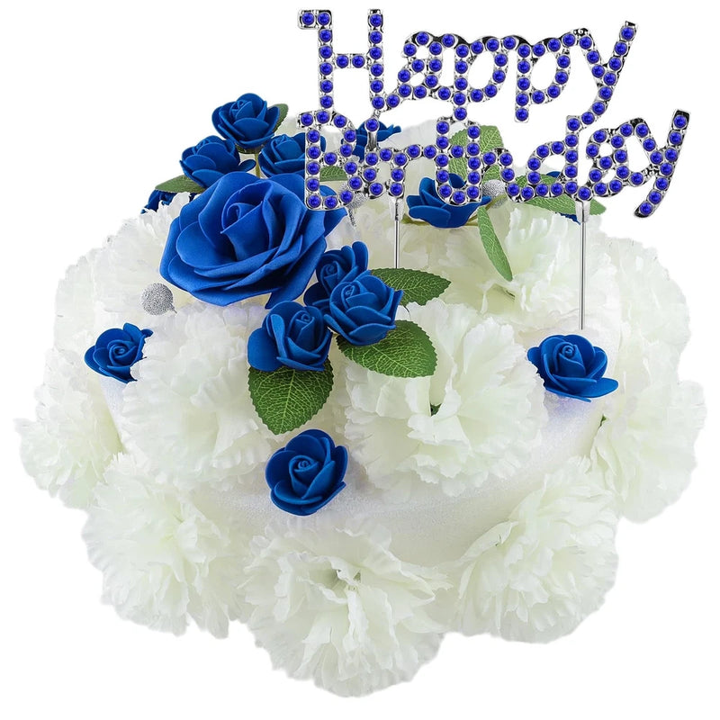 Artificial memorial flower cake with white blooms, blue roses, and jeweled letter topper