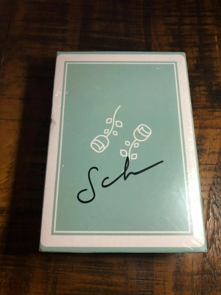 Collector's box playing cards with pale green card-back design and black signature