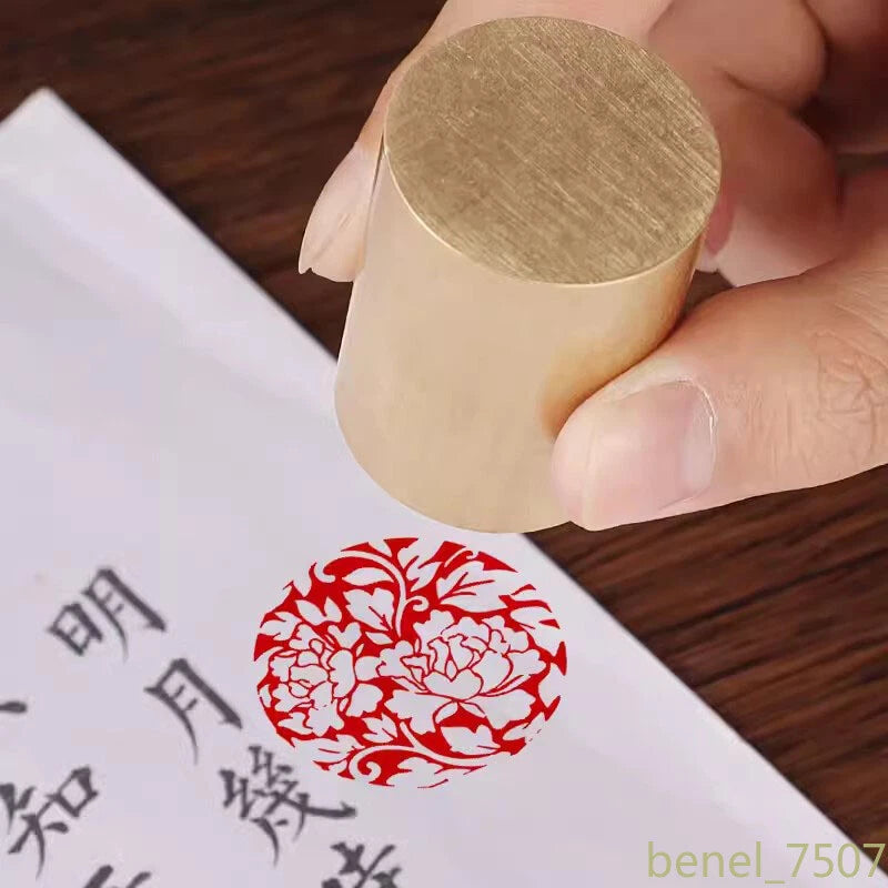 Brass sealing stamp with engraved peony flower, hand pressing onto red seal on paper