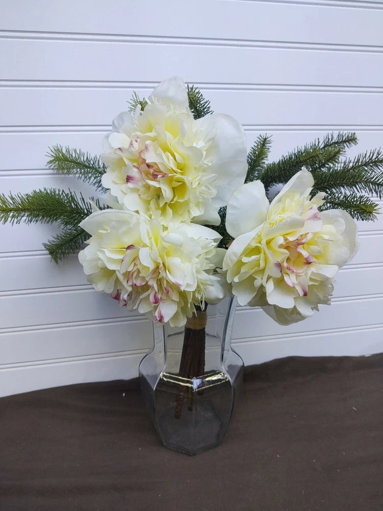 Artificial silk peony and evergreen bouquet with white peony blooms in clear glass vase