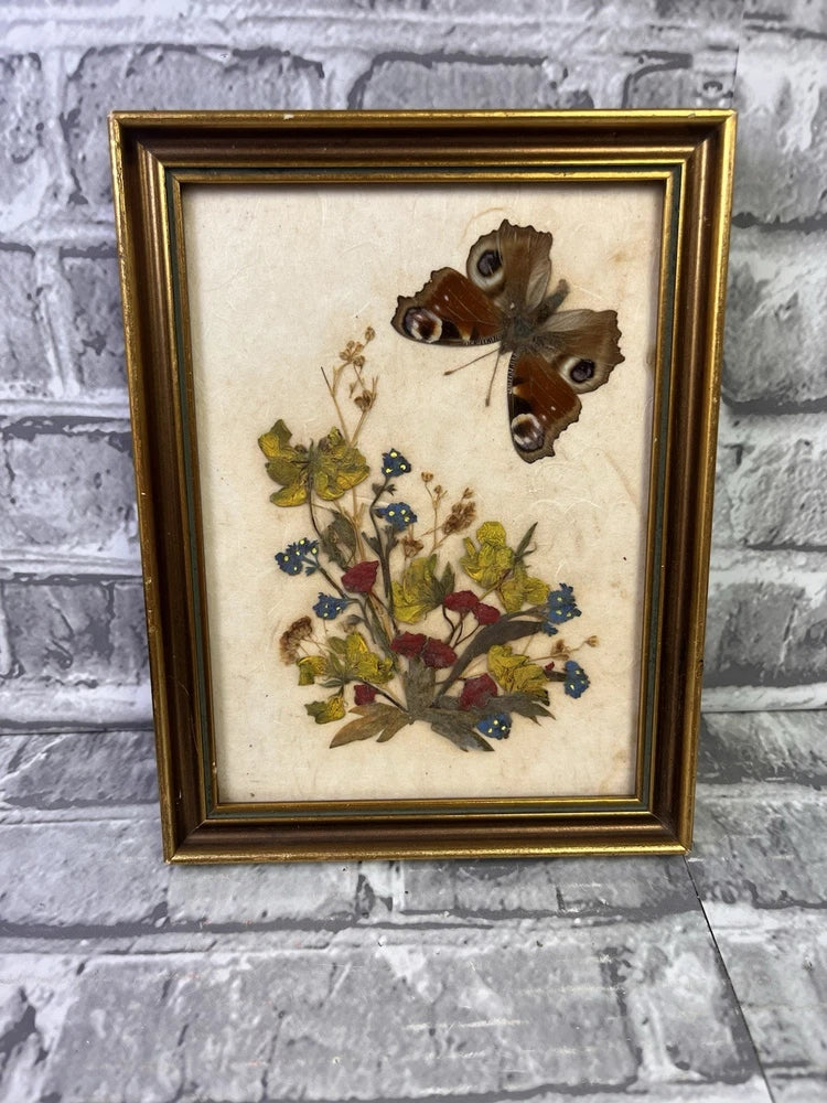 Framed pressed flowers and butterfly artwork with gold-tone border, vintage-style