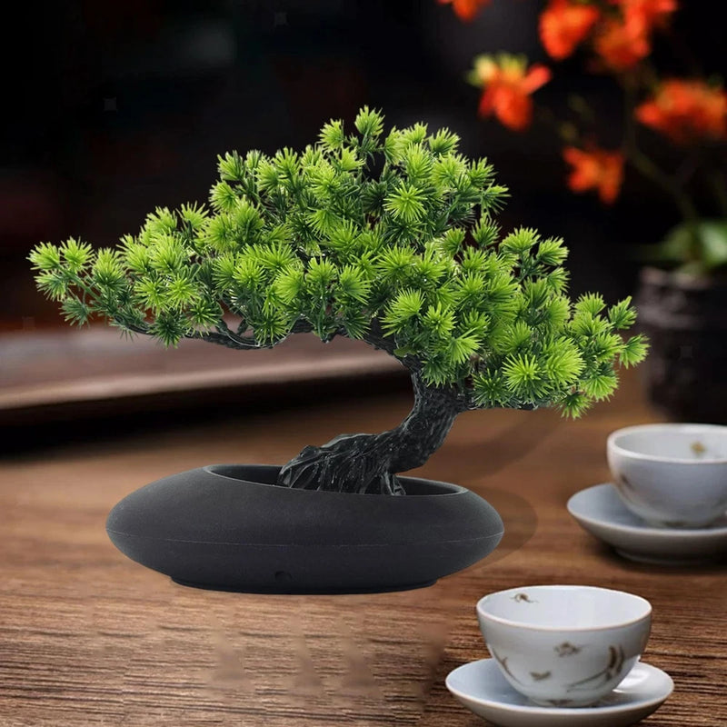 Artificial bonsai tree with green foliage in dark round pot on a tabletop