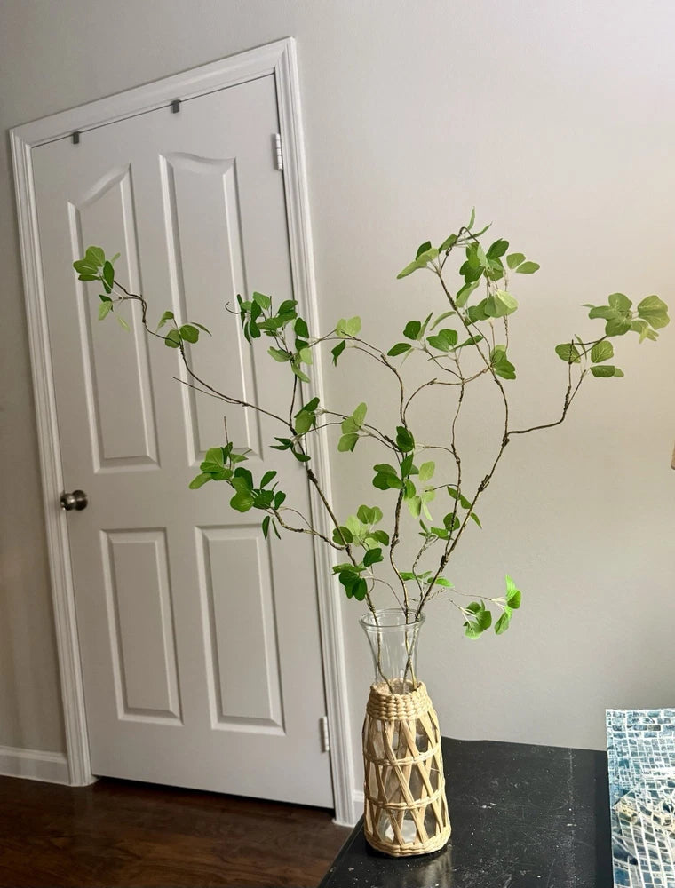 Artificial green branch houseplant with multiple leafy stems in woven basket vase