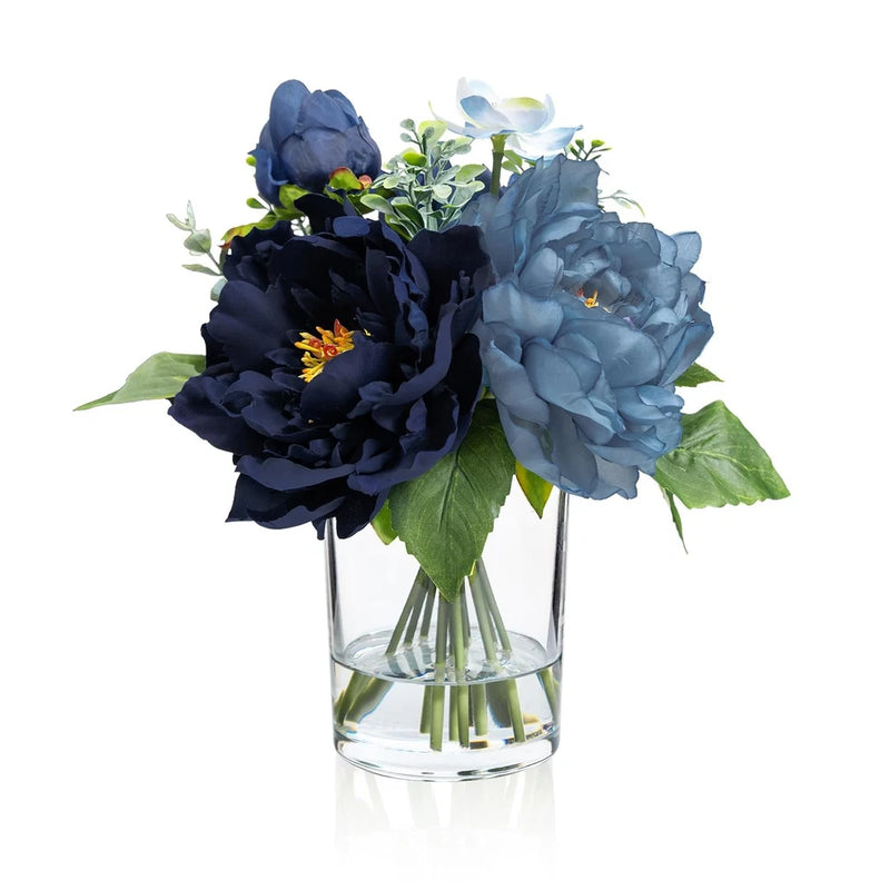 Artificial peony bouquet in clear glass vase with fake water, blue flowers and green leaves