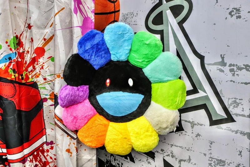 Rainbow sunflower plush pillow with black face and smile, stuffed petals in blue to green