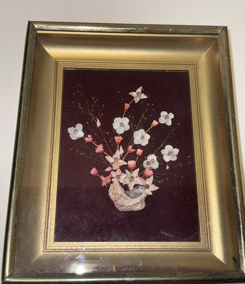 Framed shadow box with dried white and pink flowers and a small seashell centerpiece