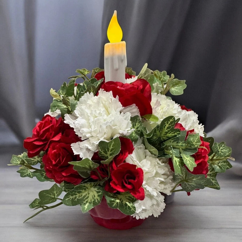 Red and white flower centerpiece with timer candle and ivy leaves, lit yellow flame