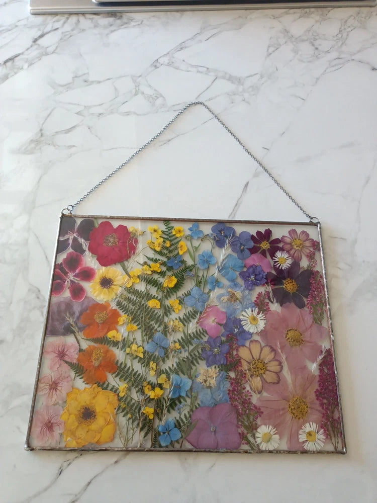 Rectangular pressed flower glass art with multicolor dried blooms on clear panel