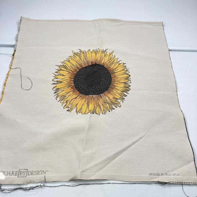 Woven upholstery fabric panel in cream with yellow sunflower and black center, fringed edges