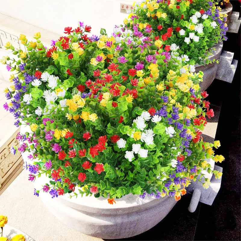 Artificial outdoor flower bundle with green leaves and mixed-color blossoms in a planter arrangement