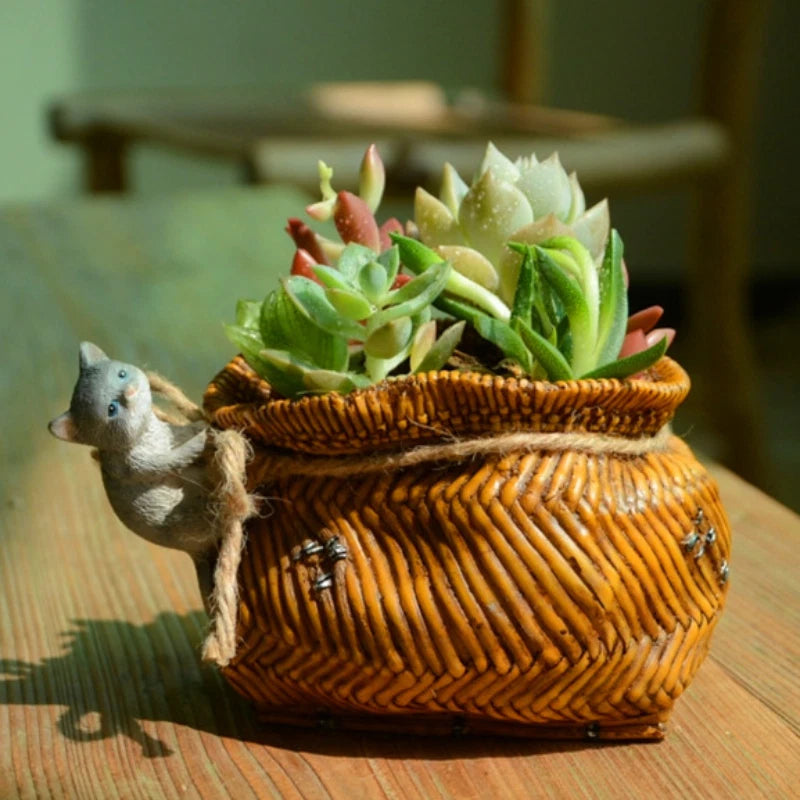 Woven bamboo cat planter basket with succulent plants and small cat figurine on the side