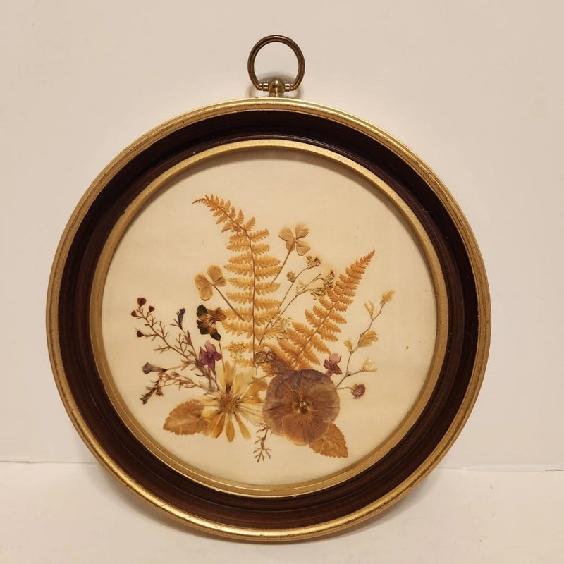 Round dried flower wall hanging with gold-tone frame and pressed botanical blooms