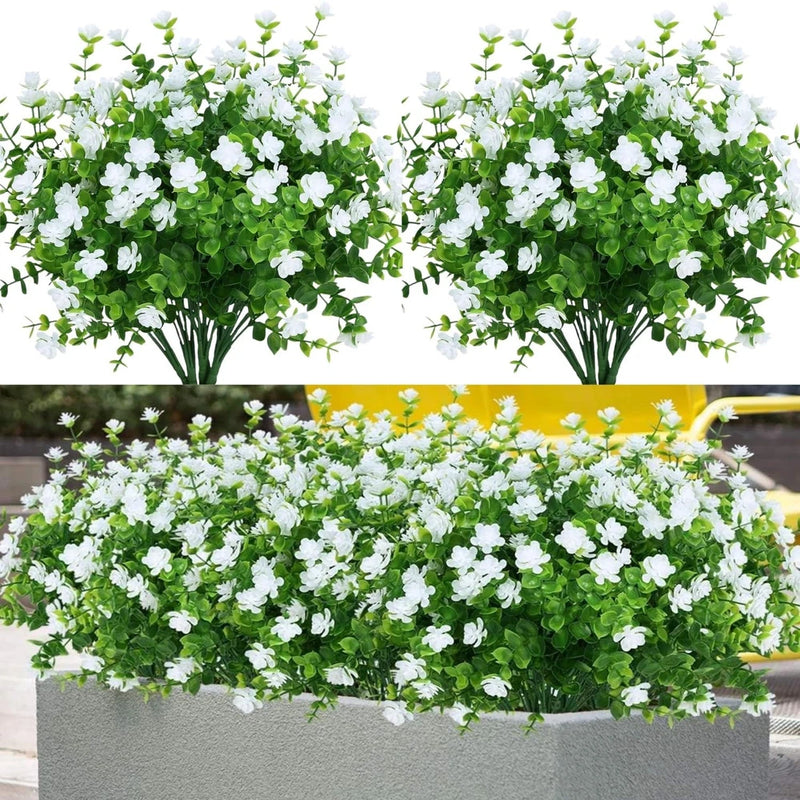 Artificial fake plant bundles with white blossoms and green leaves in a gray planter