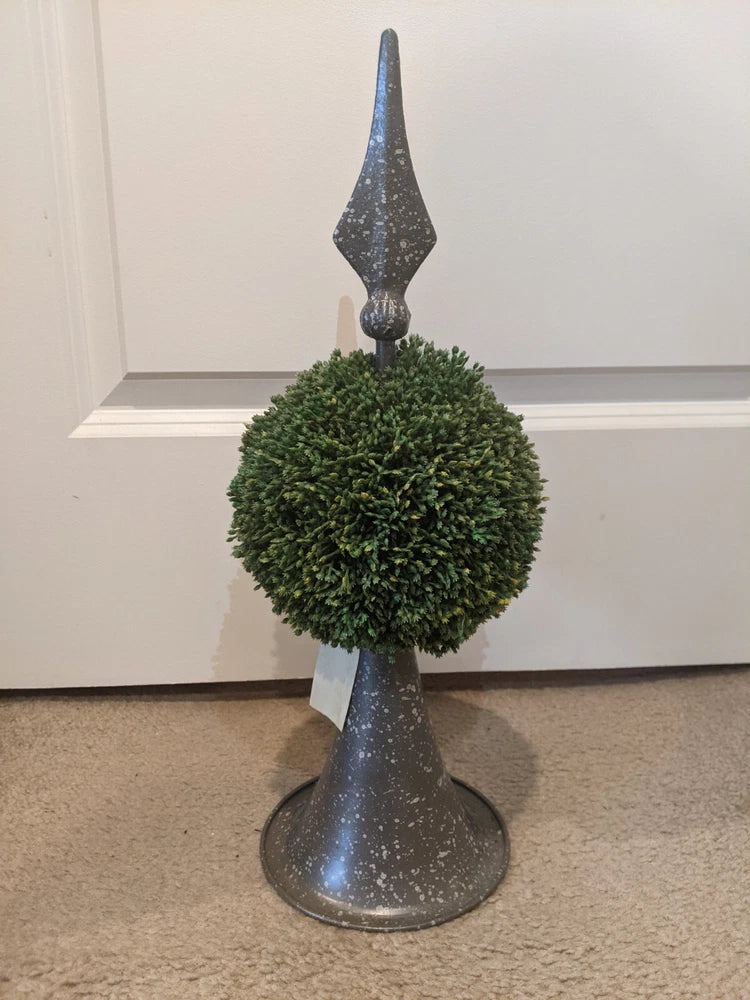 Green grass ball topiary on dark metal stand with pointed finial