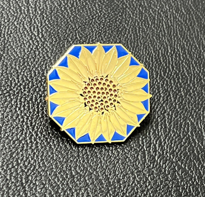 Sunflower lapel pin with blue enamel border and gold sunflower center, round detailed design