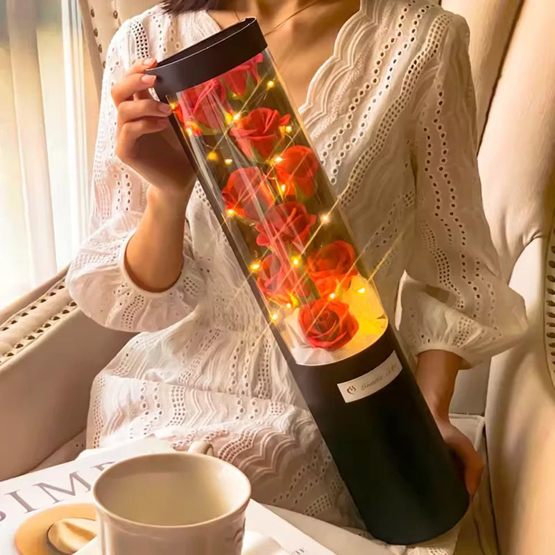 Tall gift box with red roses and warm LED lights, wrapped in dark sleeve