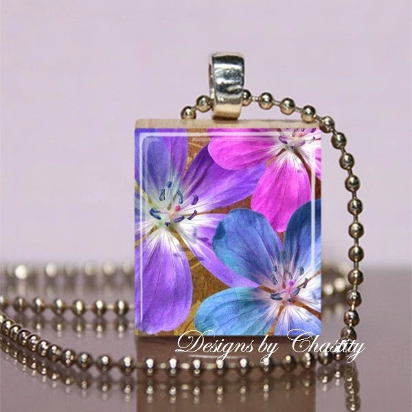 Square lily flower pendant necklace with blue, pink, and purple floral artwork and silver chain.
