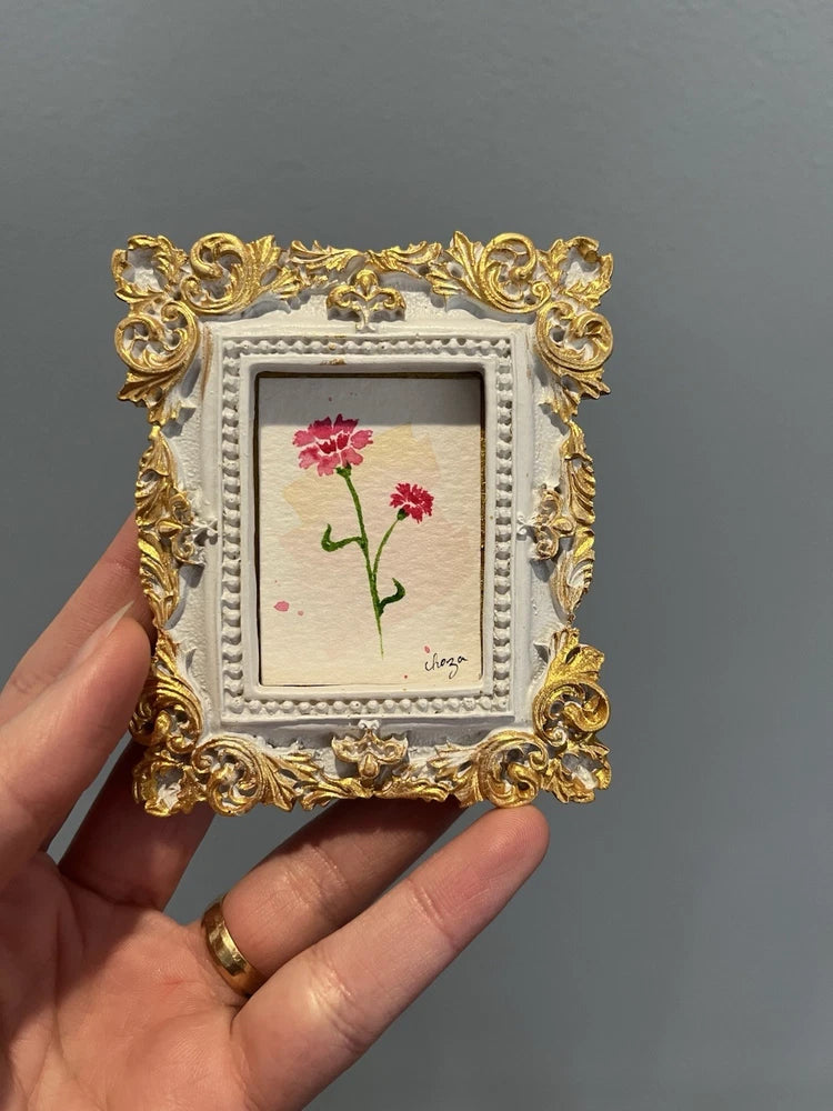 Ornate gold-framed miniature watercolor painting of red carnation blooms