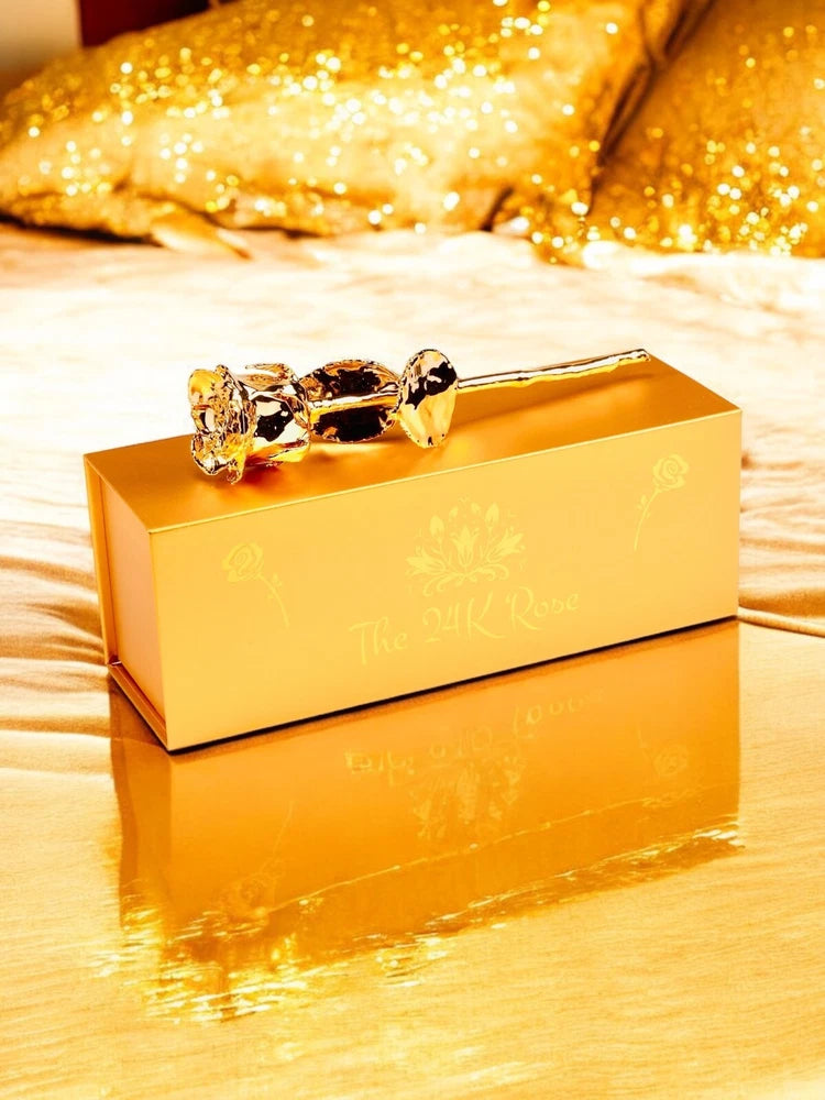 Gold-tone ring with clear and dark stones resting on a gold gift box