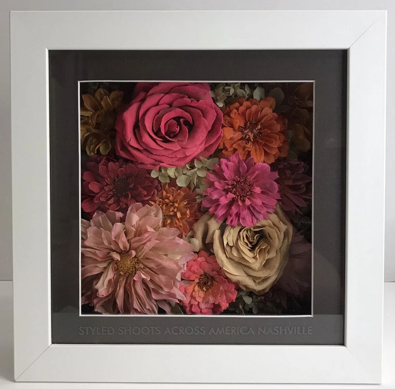 Dried flower shadow box wall art with multi-color blooms in a dark frame