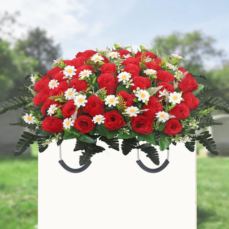 Artificial flower saddle with red roses and white daisies, green foliage on white base.