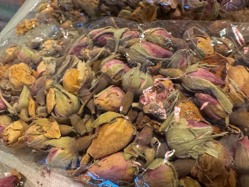 Dried whole rose buds in mixed pink, yellow, and brown petals in a clear bag
