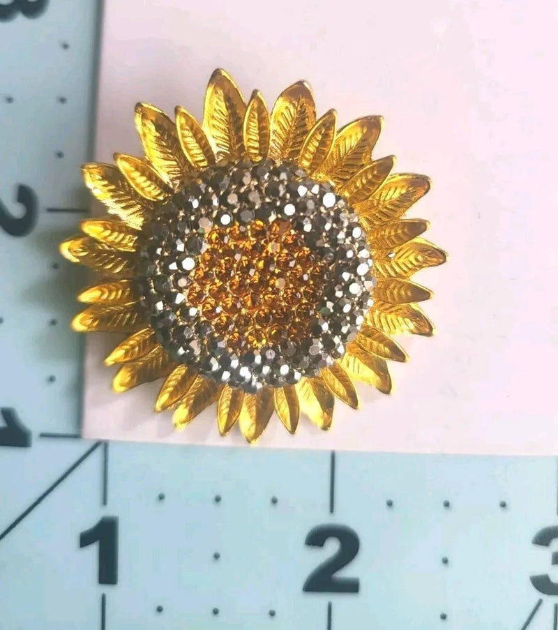 Sunflower brooch pin with gold-tone petals and amber rhinestone center, circular sparkle detail