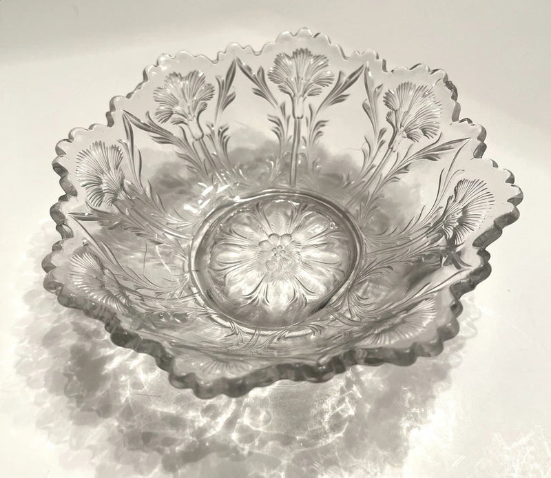 Clear pressed glass bowl with raised carnation floral pattern and scalloped rim