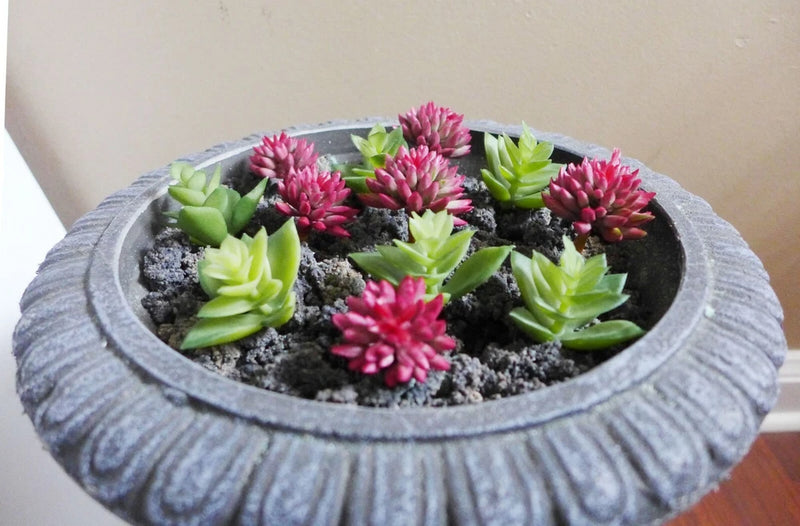 Artificial succulent plants in gray round pot, mix of green rosettes and pink flowers