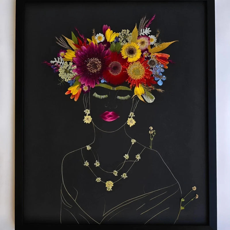 Framed pressed dried flower art with colorful bouquet above outlined face and necklace