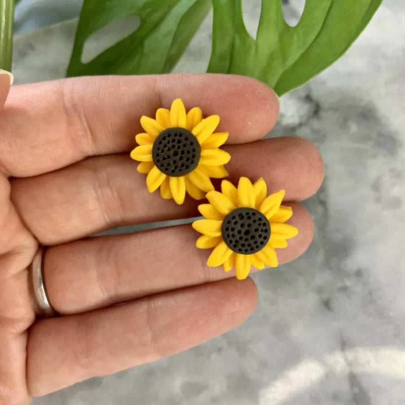 Sunflower stud earrings with yellow petals and dark circular centers, polymer clay style