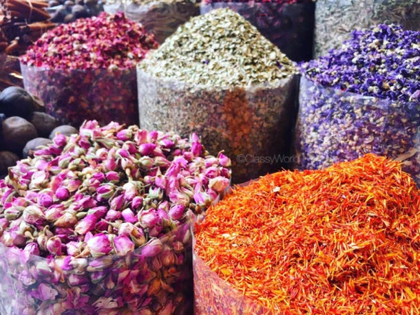 Assorted dried petals in small piles: pink, purple, and orange strands in containers