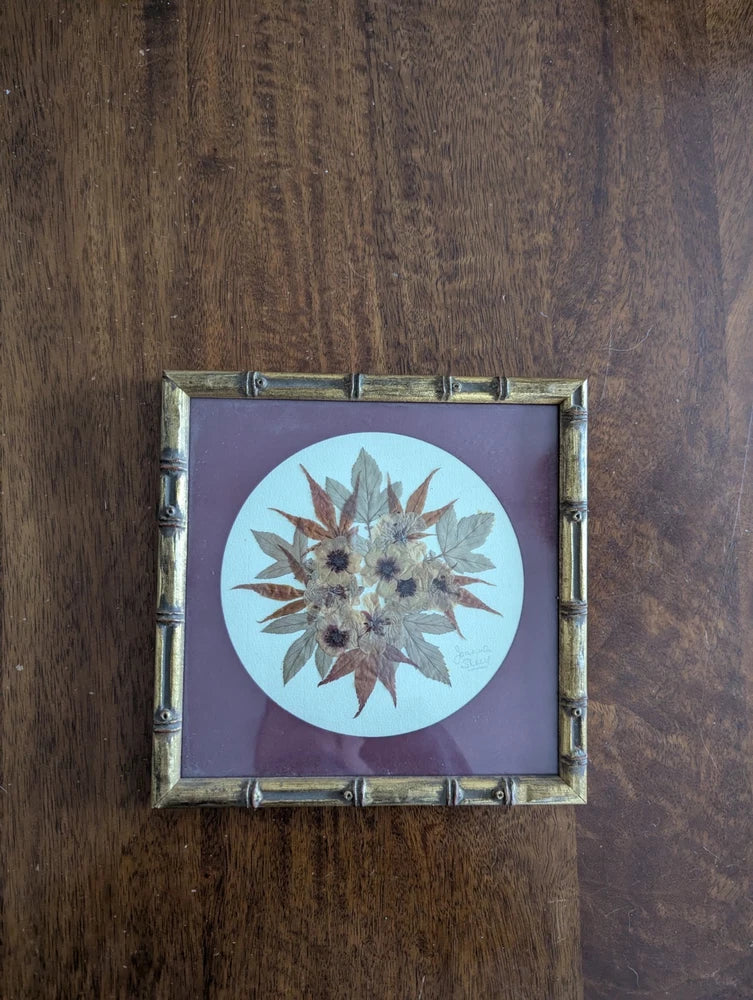 Bamboo-style framed dried flower art with circular pressed flowers in purple background