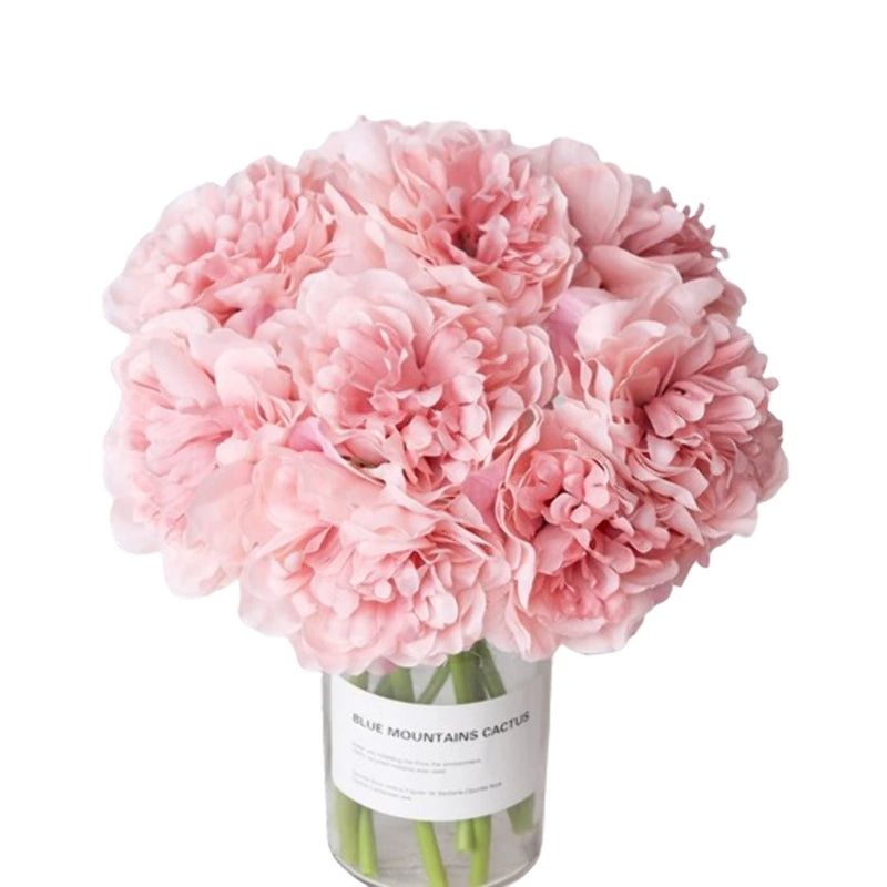 Pink artificial silk peony bouquet in clear vase with green stems