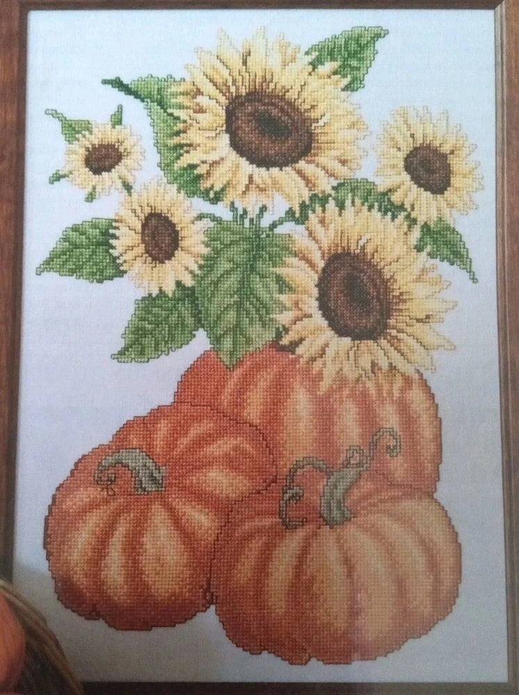 Cross stitch pattern featuring yellow sunflowers and orange pumpkins with green leaves