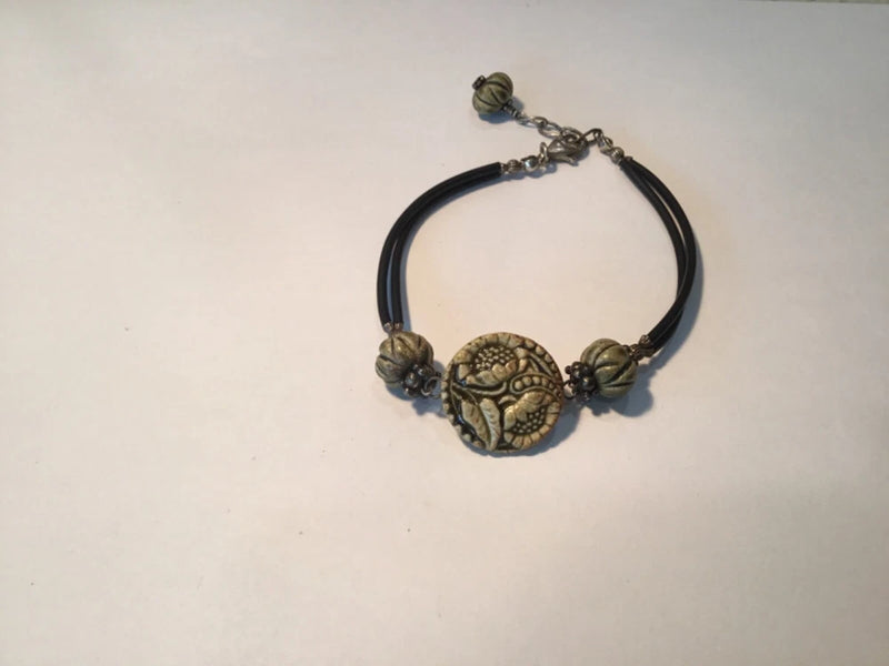 Sunflower beaded bracelet with dark cord and ornate brass-tone flower charm centerpiece