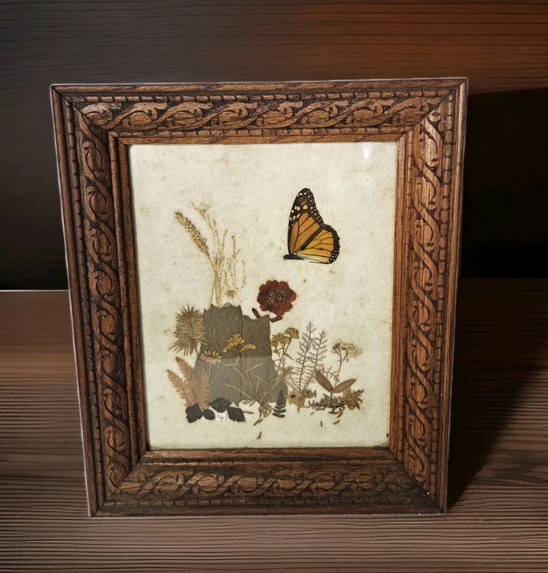 Framed pressed flower artwork with butterfly and ornate wooden frame