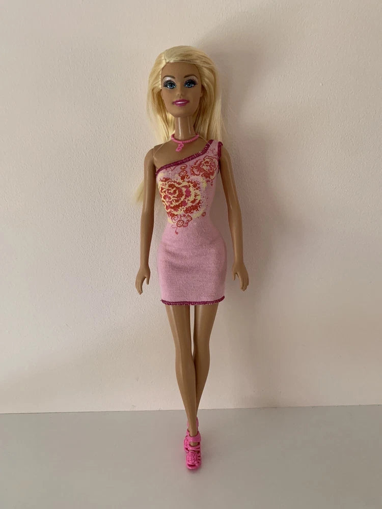 Fashion doll wearing pink sleeveless floral dress and pink heels